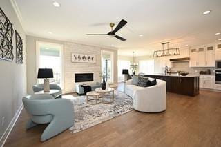 living room featuring ceiling fan with notable chandelier, a fireplace, and dark hardwood / wood-style floors