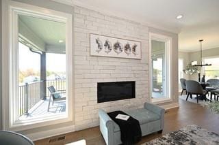 living room featuring a healthy amount of sunlight, an inviting chandelier, hardwood / wood-style floors, and a stone fireplace