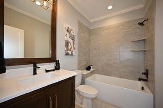 full bathroom with vanity, tiled shower / bath combo, ornamental molding, and toilet