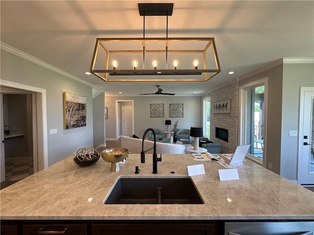 12850 N Arbor Way, Platte City, MO 64079 - kitchen featuring open floor plan, light stone counters, a large fireplace, a center island with sink, and crown molding