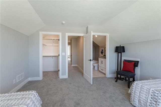 12850 N Arbor Way, Platte City, MO 64079 - bedroom with vaulted ceiling, a walk in closet, light colored carpet, a closet, and a textured ceiling