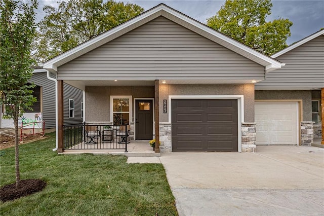 view of front of property featuring a front lawn, covered porch, and a garage