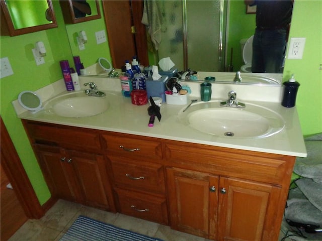 bathroom featuring double vanity, a sink, and a shower with door