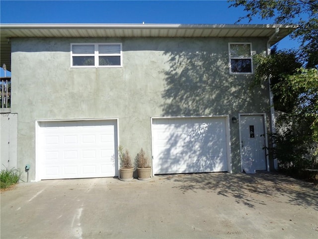 exterior space featuring driveway, an attached garage, and stucco siding