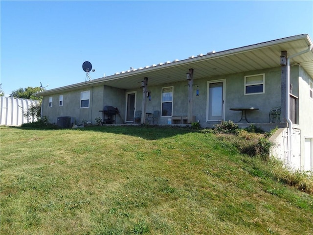 back of property with a lawn, fence, and stucco siding