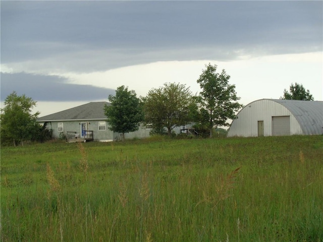 view of yard featuring a garage, a pole building, and an outdoor structure