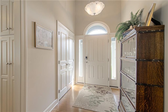 entryway with light hardwood / wood-style flooring and a towering ceiling