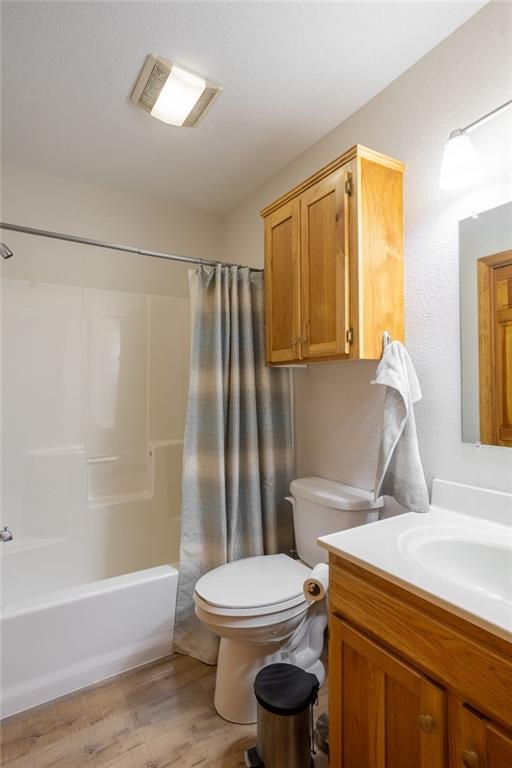 full bathroom featuring wood-type flooring, vanity, toilet, and shower / bathtub combination with curtain