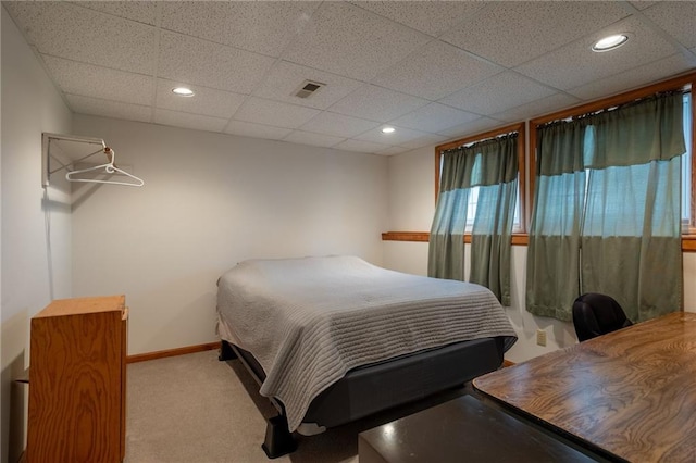 carpeted bedroom featuring a drop ceiling