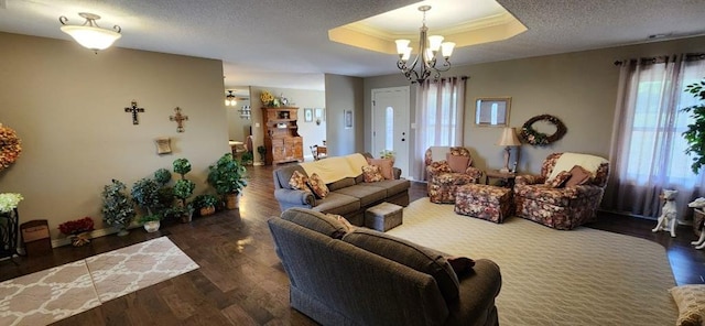 living room with a chandelier, crown molding, dark wood-type flooring, and a tray ceiling