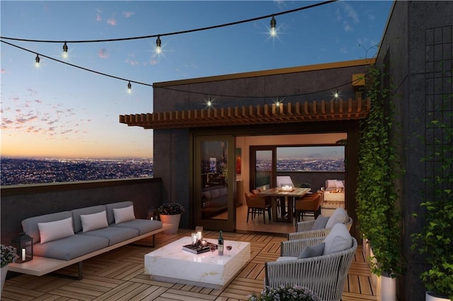 patio terrace at dusk featuring a wooden deck and an outdoor living space with a fire pit