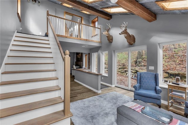 living area with a skylight, stairway, plenty of natural light, and wood finished floors