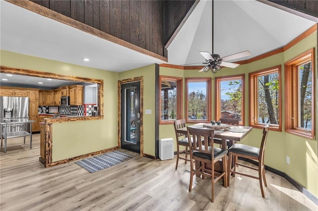 dining space with crown molding, light wood finished floors, recessed lighting, vaulted ceiling, and baseboards