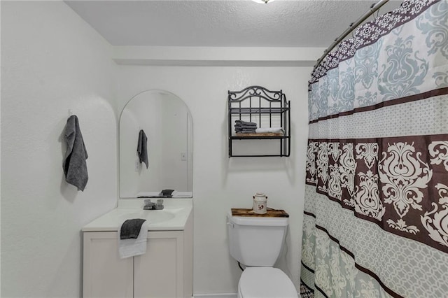 bathroom featuring a shower with curtain, vanity, toilet, and a textured ceiling