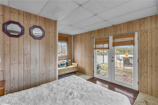 bedroom featuring access to outside, wood walls, and wood finished floors