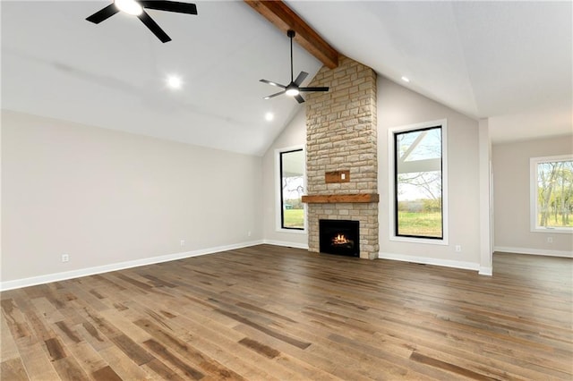 unfurnished living room featuring a stone fireplace, hardwood / wood-style floors, and beamed ceiling