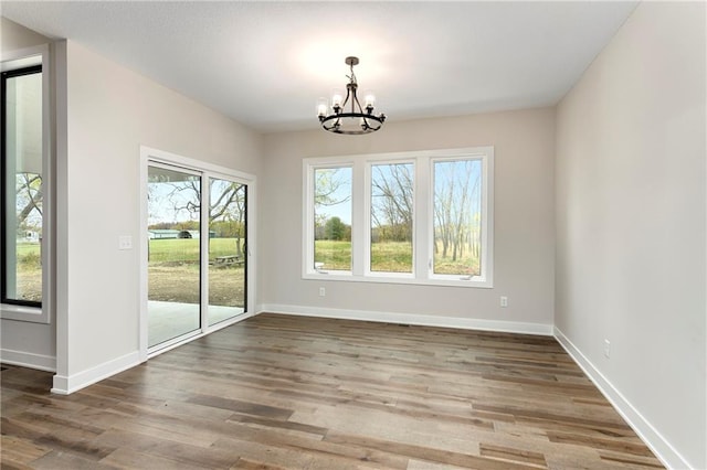 unfurnished dining area featuring dark hardwood / wood-style flooring and an inviting chandelier