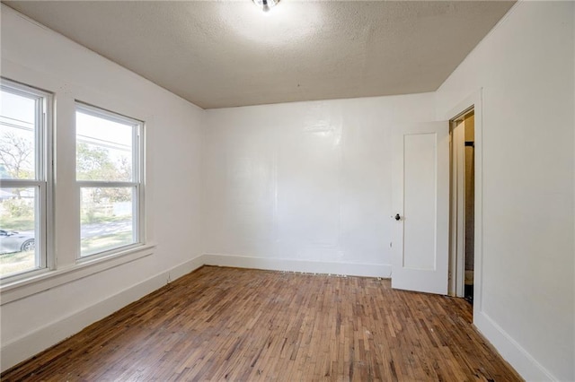 spare room featuring hardwood / wood-style flooring and a textured ceiling