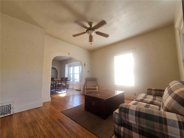 unfurnished living room featuring ceiling fan, wood-type flooring, and a textured ceiling