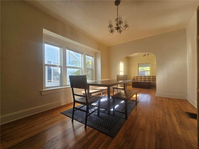 dining space featuring dark hardwood / wood-style flooring, a chandelier, and a textured ceiling