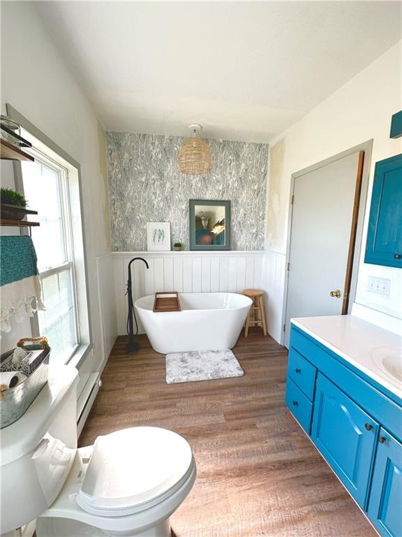 bathroom with vanity, hardwood / wood-style flooring, a bath, toilet, and a baseboard heating unit