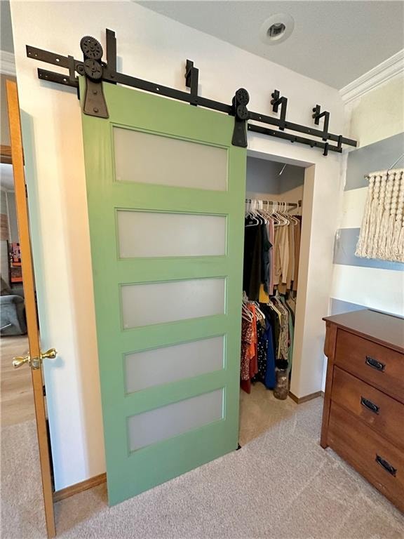 spacious closet featuring light colored carpet and a barn door