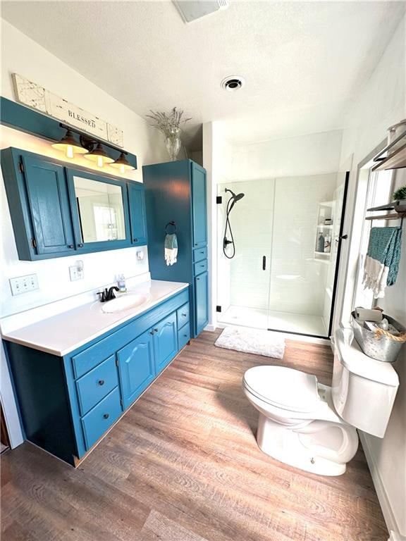 bathroom featuring vanity, hardwood / wood-style floors, toilet, and a shower with door