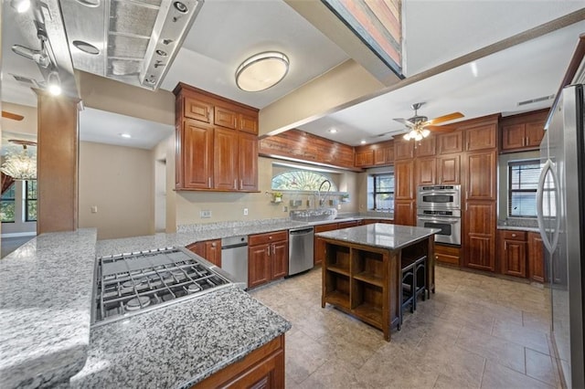 kitchen with appliances with stainless steel finishes, a center island, kitchen peninsula, and light stone countertops