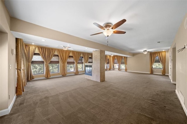 unfurnished living room with ceiling fan, carpet, and a wealth of natural light