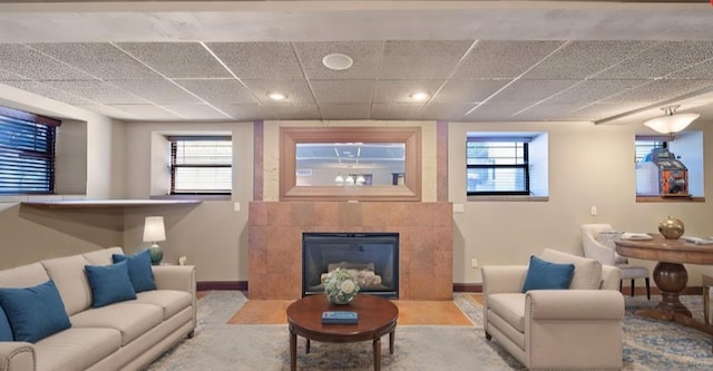 living room featuring a healthy amount of sunlight, a fireplace, and a drop ceiling