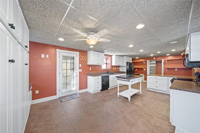 kitchen featuring white cabinetry, a breakfast bar, a center island, and black appliances