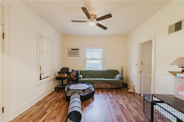 living area featuring an AC wall unit, ceiling fan, and hardwood / wood-style flooring