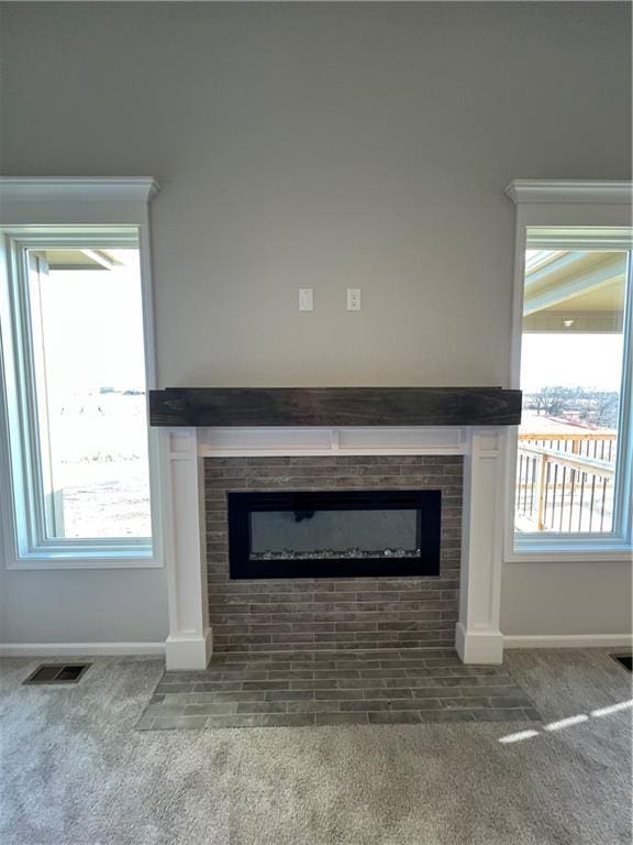 interior details with a tiled fireplace and carpet floors