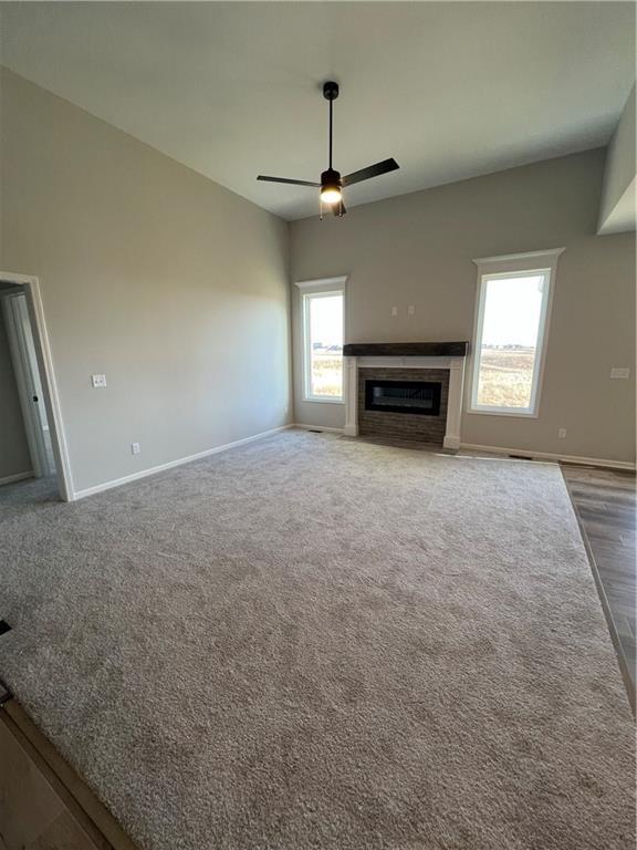 unfurnished living room featuring carpet, ceiling fan, and a wealth of natural light