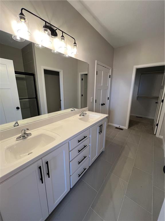 bathroom with tile patterned floors, vanity, and an enclosed shower