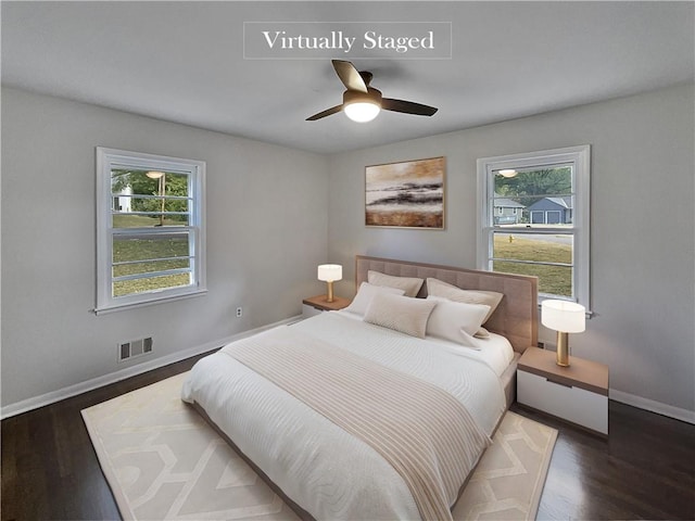 bedroom with ceiling fan, dark hardwood / wood-style flooring, and multiple windows