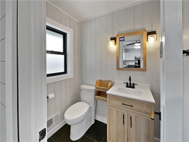 bathroom featuring wooden walls, vanity, toilet, and tile patterned floors