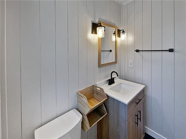 bathroom with wooden walls, vanity, and toilet