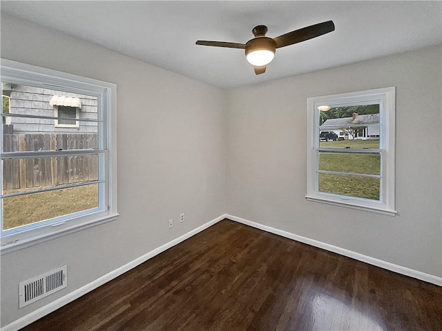 empty room featuring a wealth of natural light, ceiling fan, and hardwood / wood-style floors