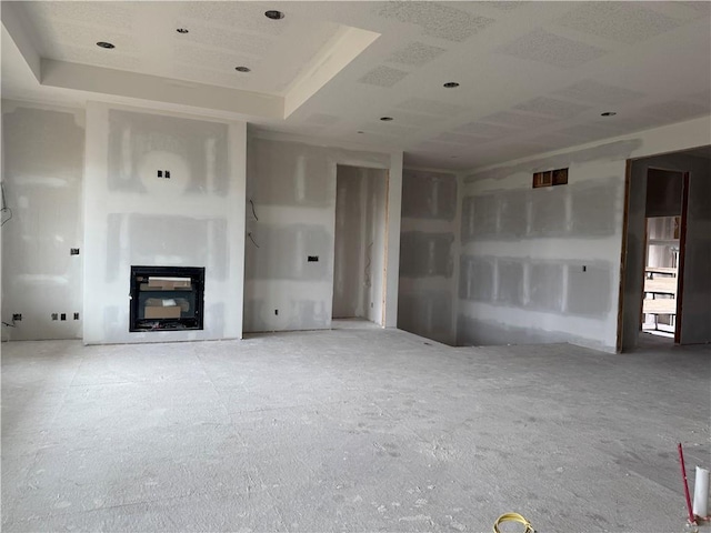 unfurnished living room featuring a glass covered fireplace and a raised ceiling