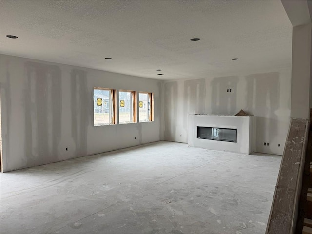 unfurnished living room with a textured ceiling and a glass covered fireplace