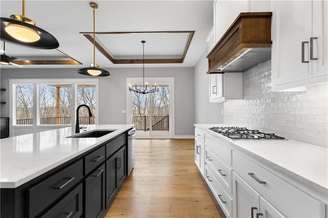 kitchen with custom exhaust hood, a raised ceiling, a sink, and light countertops