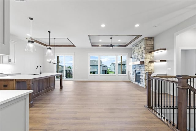1617 SW Arbor Park Dr, Lees Summit, MO 64082 - kitchen featuring a tray ceiling, light countertops, recessed lighting, light wood finished floors, and white cabinets