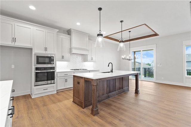 1617 SW Arbor Park Dr, Lees Summit, MO 64082 - kitchen featuring appliances with stainless steel finishes, a tray ceiling, light wood-type flooring, light countertops, and backsplash