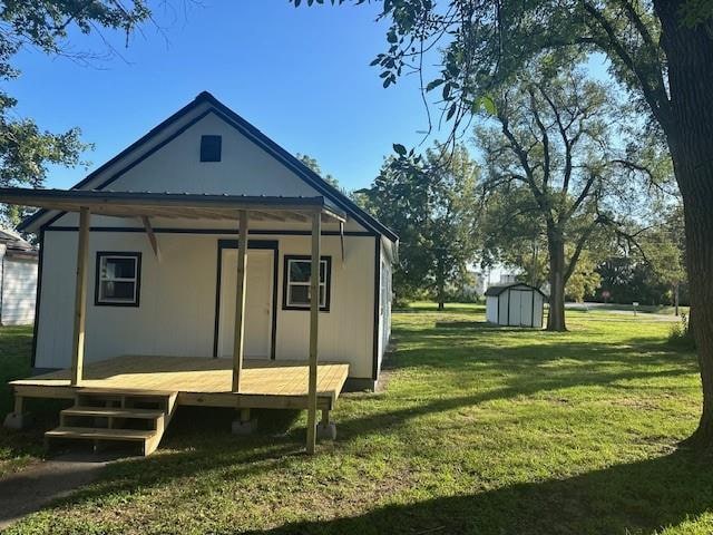 rear view of house with a lawn and a storage unit