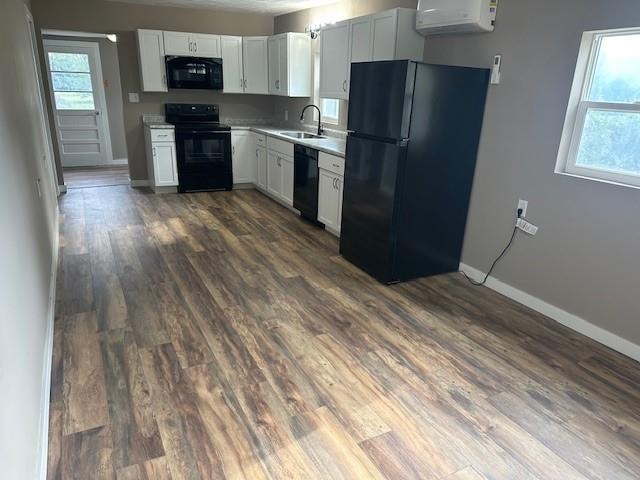 kitchen with dark hardwood / wood-style floors, black appliances, white cabinetry, and sink