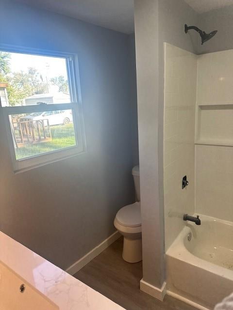 bathroom with hardwood / wood-style flooring, bathing tub / shower combination, and toilet