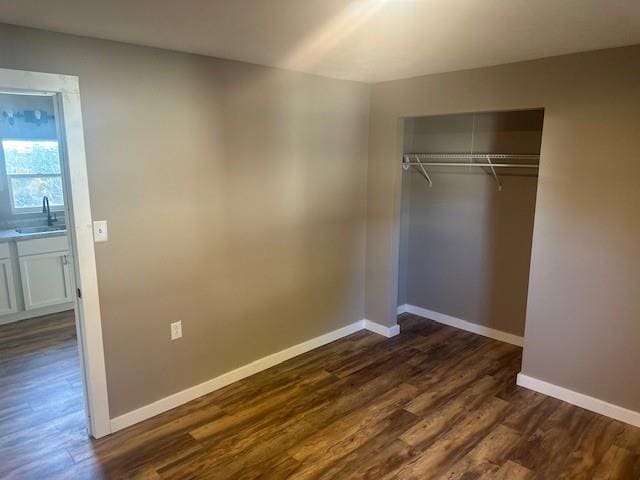 unfurnished bedroom with a closet, dark hardwood / wood-style floors, and sink