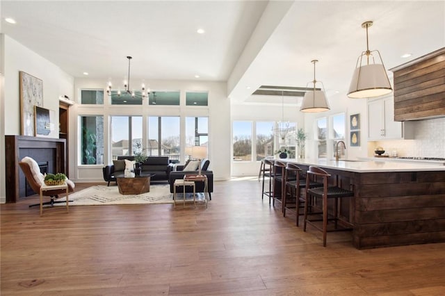 kitchen with sink, decorative light fixtures, dark wood-type flooring, white cabinetry, and a breakfast bar area