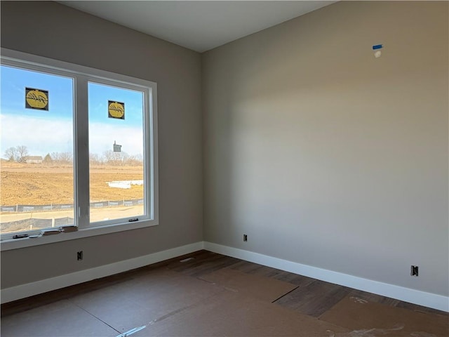 spare room featuring dark wood finished floors and baseboards